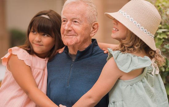 amenities-youll-love-4 Senior resident smiles with granddaughters at Summerfield of Redlands Memory Care in Redlands, CA