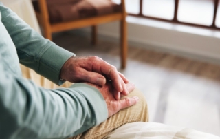 Senior sitting with hands folded, thinking.