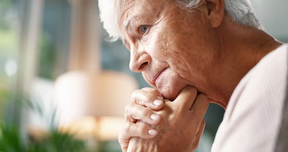 Senior woman, unhappy and thinking in home